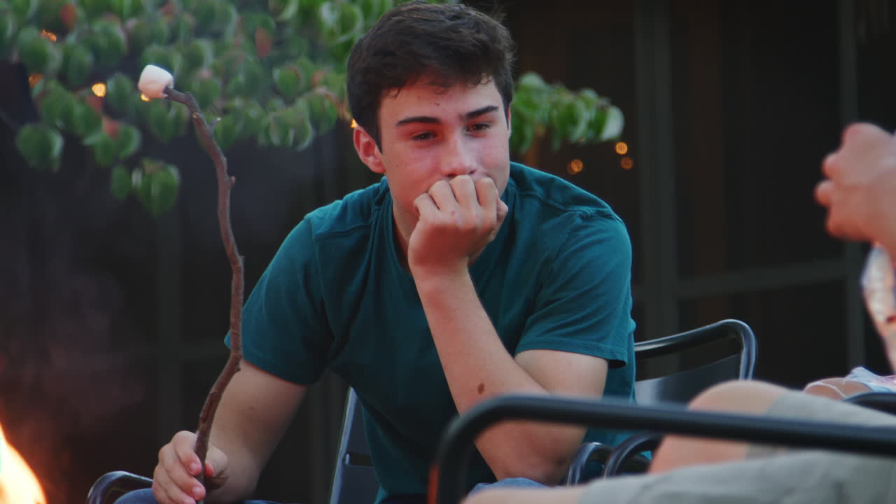 십대 친구 들 이 벽난로 에서 마쉬멜로 를 토스 하고 있다