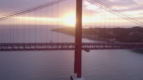 Die-Sonne-Zeigt-Sich-Hinter-Der-Säule-Der-Brücke-Ponte-25-De-April-Bei-Sonnenaufgang,-Luftaufnahme