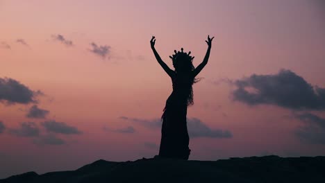 side view of sexy, elegant and erotic arabian woman performing belly dance on the beach during golden hour. silhouette.