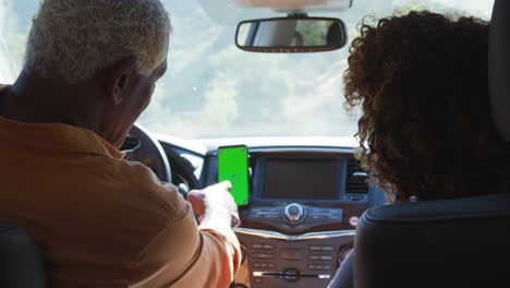 una pareja de ancianos afroamericanos en un viaje por el campo usando navegación por satélite en un teléfono móvil