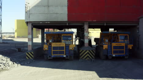 camiones de minería bajo una estructura de carga