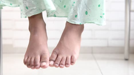 child's bare feet hanging down