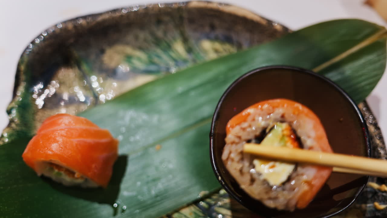 Close up of a woman picking up a Philadelphia sushi roll and dipping it in soy sauce