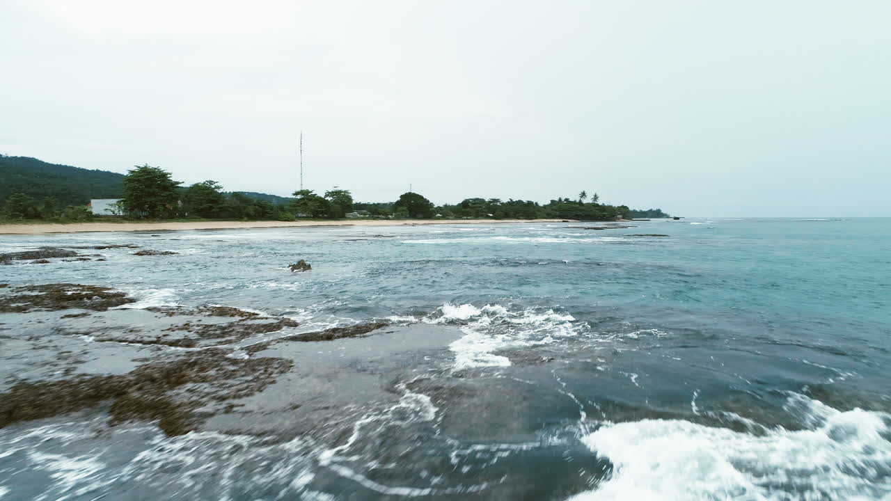 인도네시아의 펠라부한 라투 지역에서 독특한 시각으로 합쳐지는 흥미로운 패턴의 파도와 산호가 해변 위를 날고 있습니다.