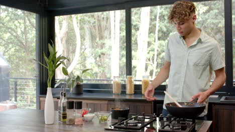 young man cooking in modern kitchen, preparing fresh ingredients with focus