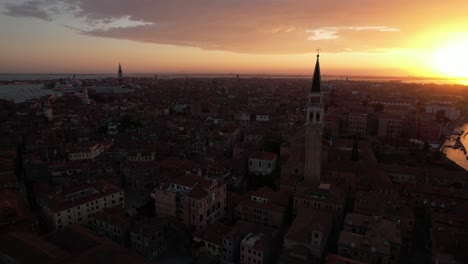 Puesta-De-Sol-En-Venecia,-Italia,-Dron-Aéreo-Sobre-La-Ciudad-Flotante-De-Canales,-Cielo-Dorado-Sol-Sobre-Edificios,-Arquitectura-De-La-Ciudad-Y-Torre-Campanile