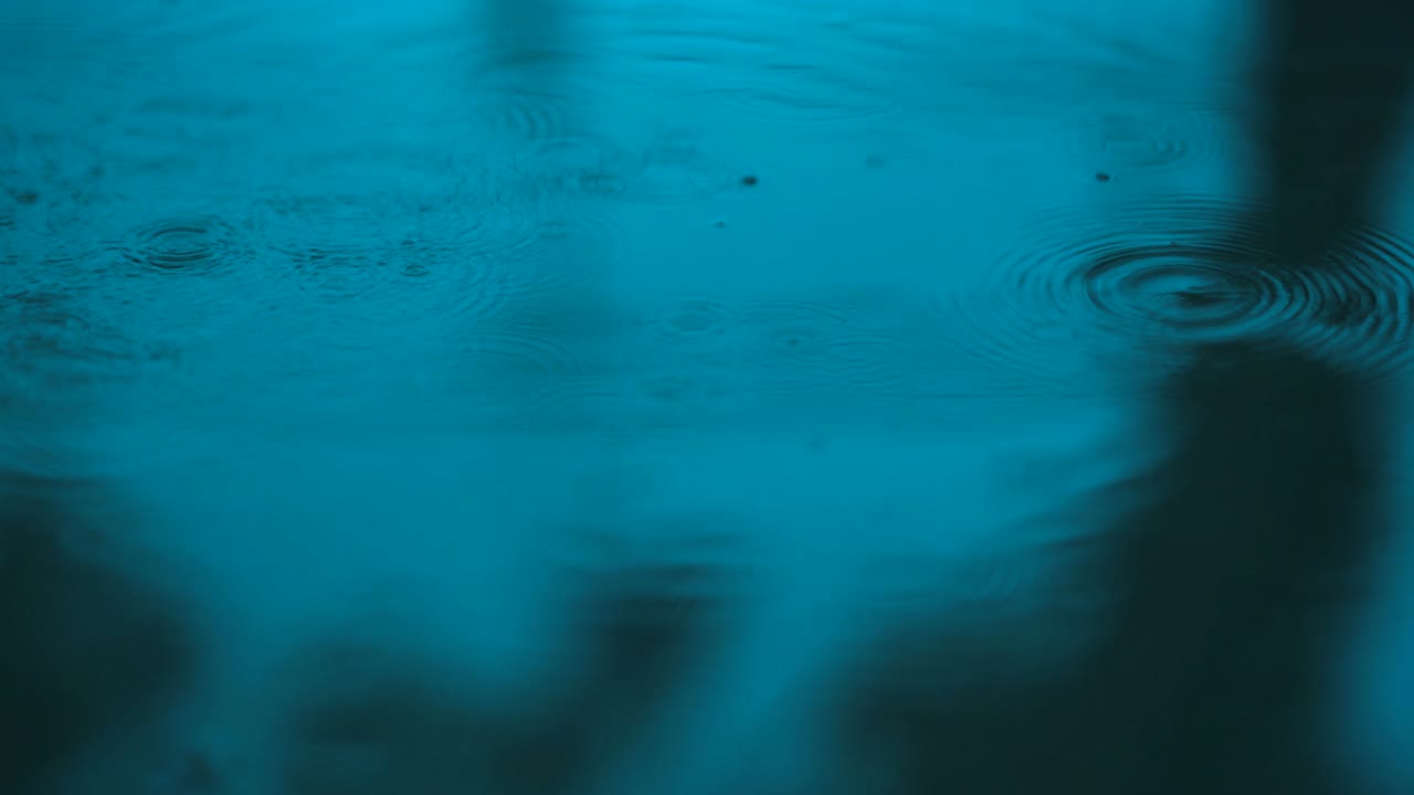 agua en movimiento lento gotas de lluvia cayendo sobre el agua sobre el suelo, hermosa superficie azul onda papel tapiz abstracto, patrón de círculo en el suelo, salpicaduras de gota de lluvia caendo y goteando en el suelo mojado