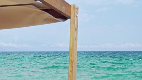 Part-of-Cabana-Sunbed,-with-beautiful-green-sea-on-the-background,-shallow-depth-of-field,-slow-motion