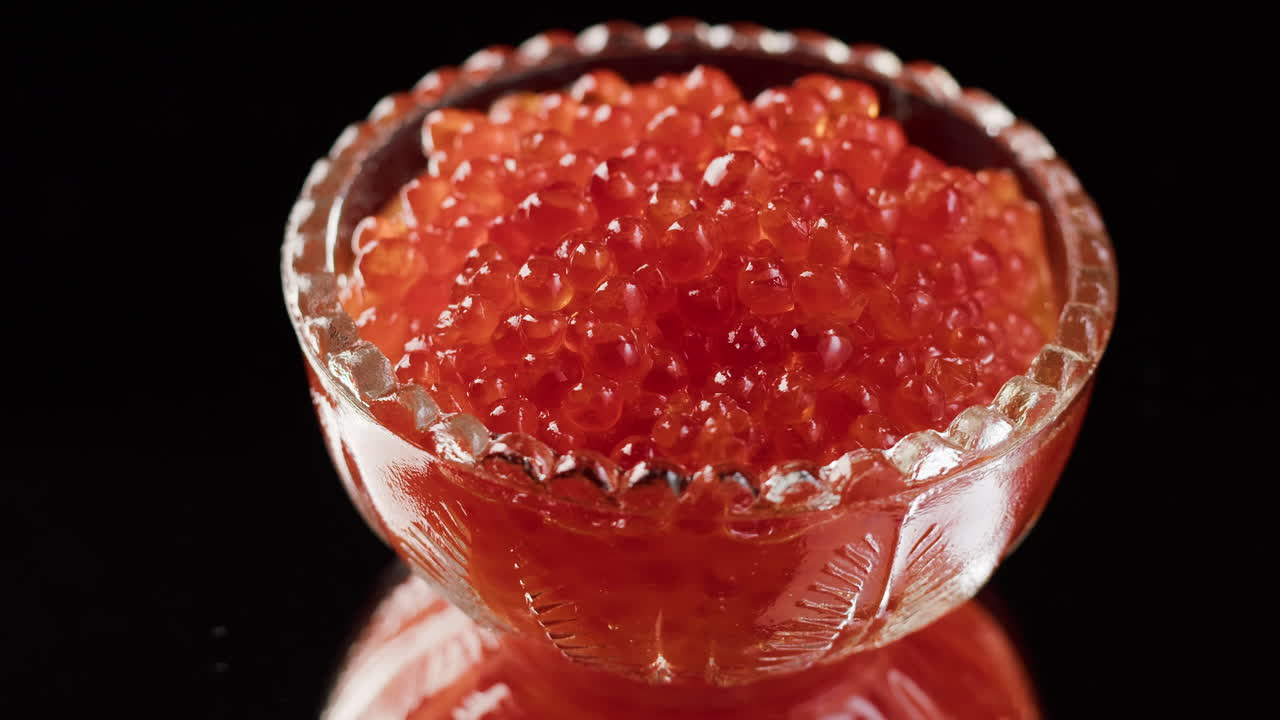 Caviar Vermelho Brilhante em uma Tigela de Vidro sobre Fundo Preto