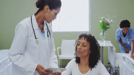 frontansicht einer afroamerikanischen ärztin, die einen medizinischen bericht mit einer behinderten patientin bespricht