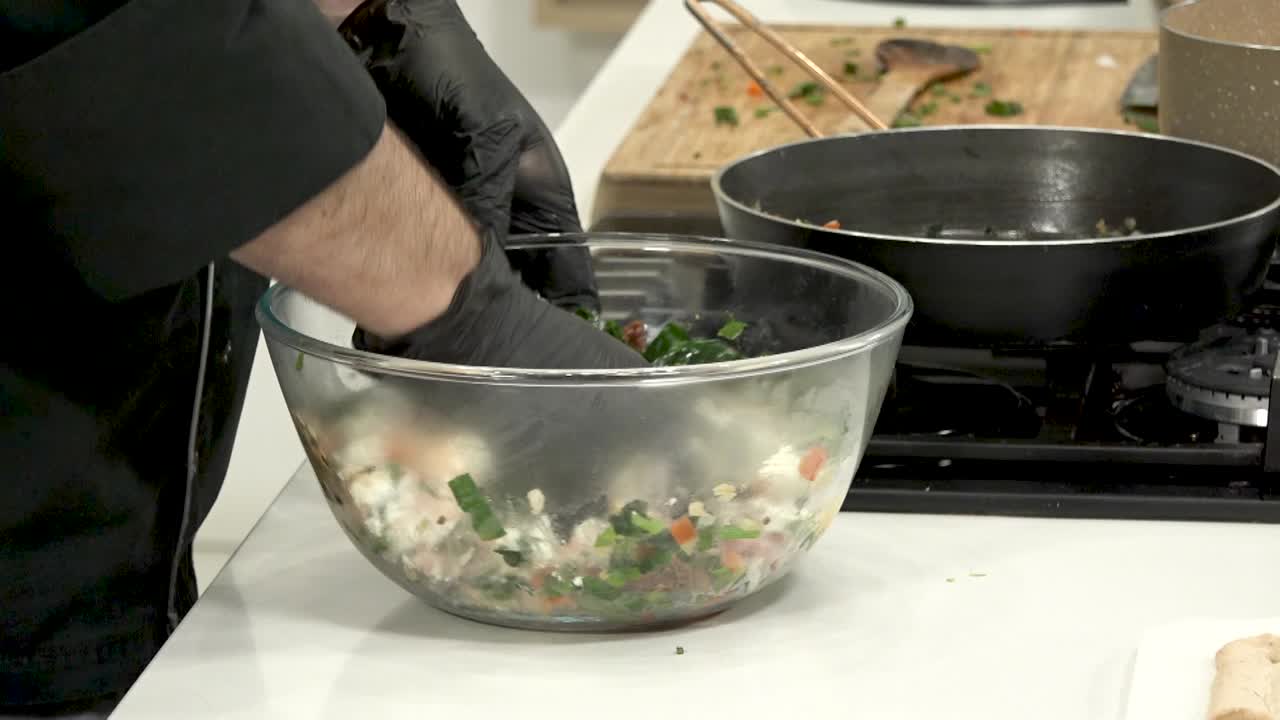 In a contemporary kitchen, a chef skillfully combines fresh vegetables in a mixing bowl. Colorful ingredients are blended together with precision, ensuring they are well mixed for a nutritious dish