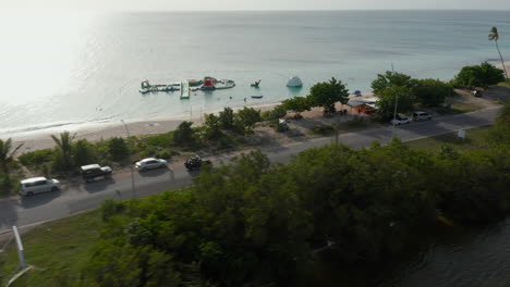 Aerial-panorama-tracking-view-tourist-in-open-roof-green-4x4-car-drive-in-scenic-tropical-Antigua-and-Bermuda-coast