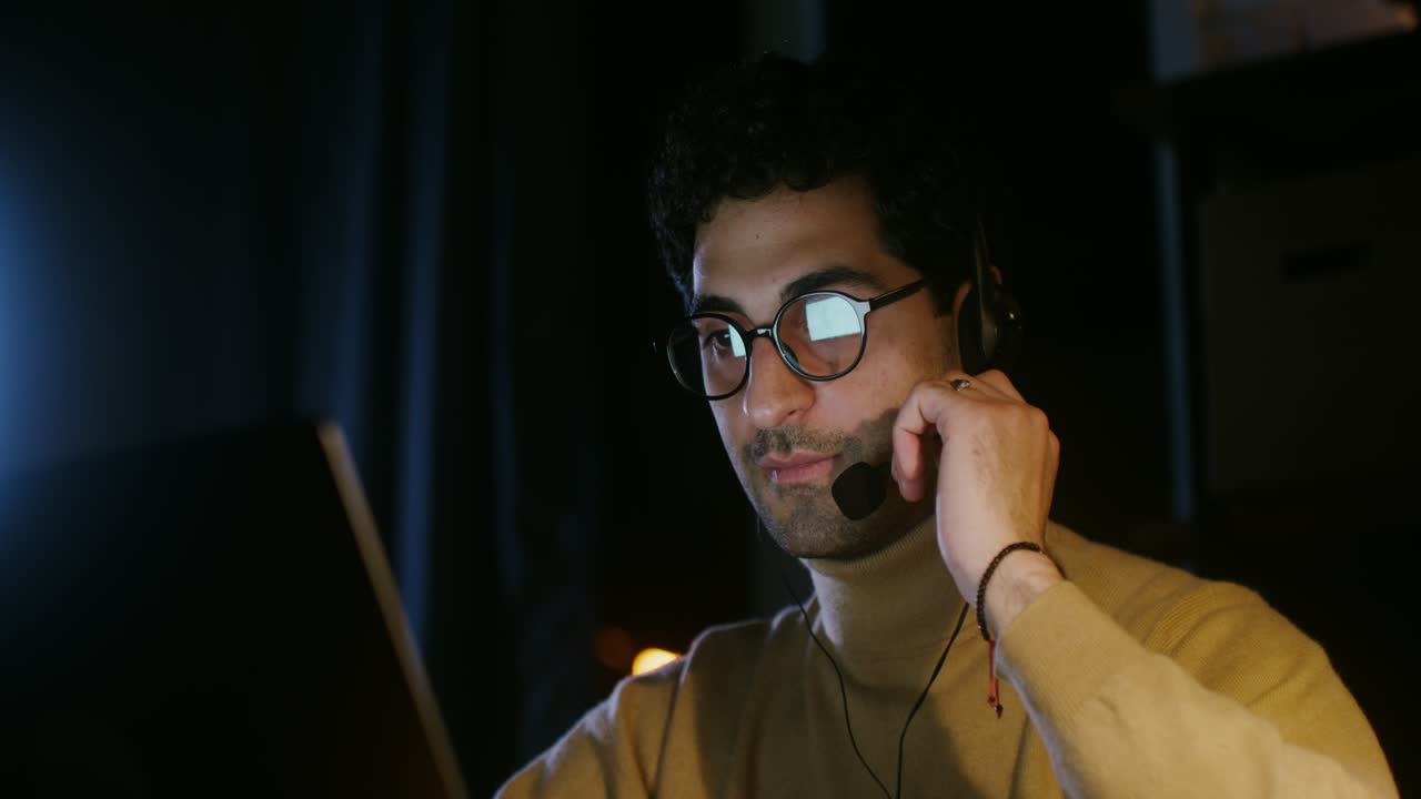 Man working on laptop at night wearing headphones
