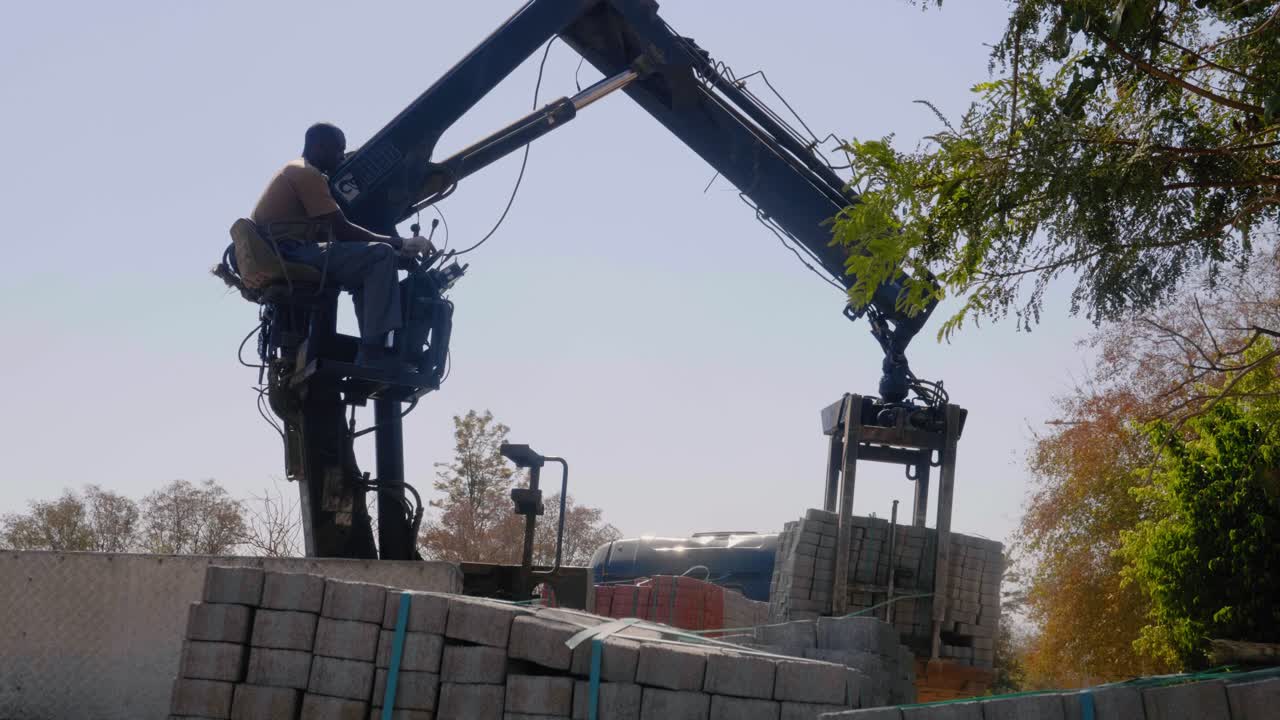 Worker Operating a Crane to Lift and Transport Bricks