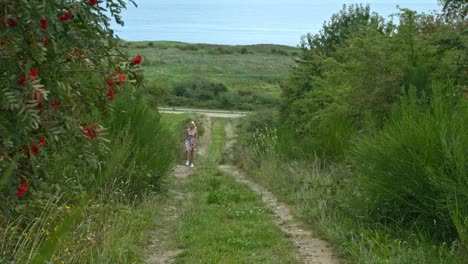 a slow zoom-in of a woman going for a leisurely walk along a nature track