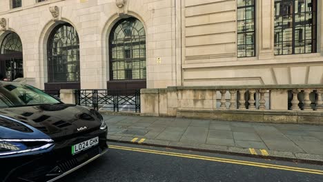 car drives past pedestrian on london street