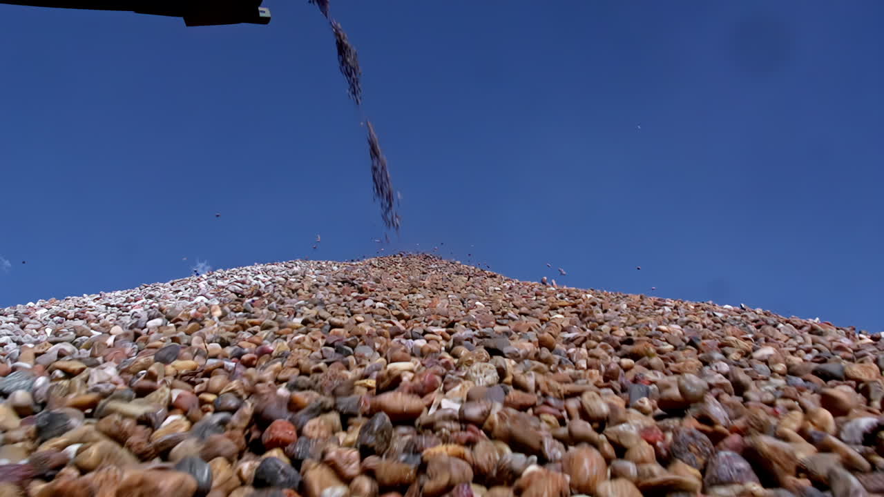 rocas rodando y deslizándose por un montón mientras un transportador arroja piedras clasificadas en el montón en una cantera - perspectiva única en cámara lenta