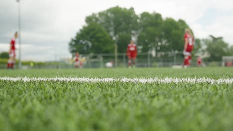 Junge-Weibliche-Fußballjugendliche-Im-Roten-Outfit,-Die-Den-Ball-Als-Aufwärmen-Vor-Dem-Spiel-Passieren