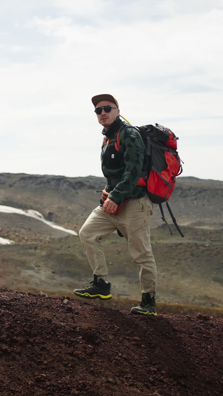 Man Hiking with Backpack and Camera on Volcanic Mountain Ridge