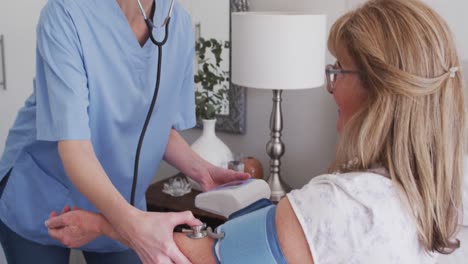 una trabajadora de la salud que comprueba la presión arterial de una anciana en casa