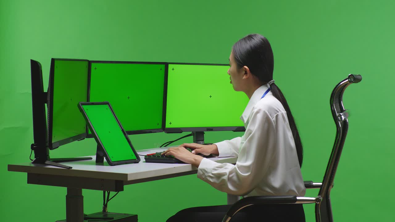 여러 개의 모니터를 가진 컴퓨터에서 일하는 여성