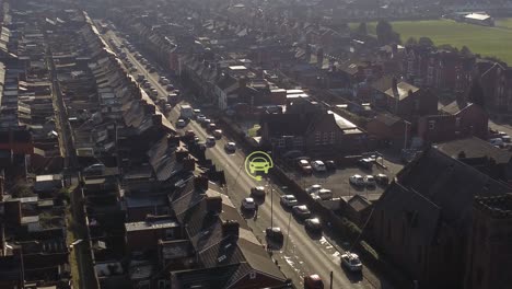 aerial view orbiting electric car charged symbol flashing above vehicle driving long road in british neighbourhood at sunrise