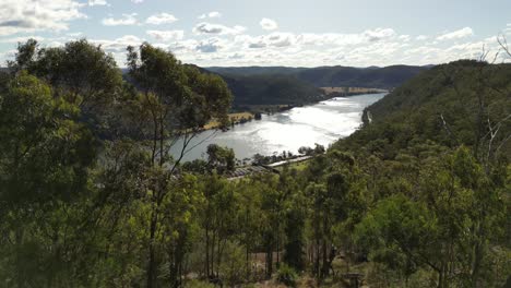 Amazing-river-reveal-from-a-drone-flying-from-Hawkins-Lookout,-Wisemans-Ferry,-New-South-Wales,-Australia,-showing-the-majestic-Hawkesbury-River-below-and-Blue-Mountains-to-the-west