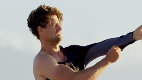 surfista masculino con traje de neopreno en la playa 4k