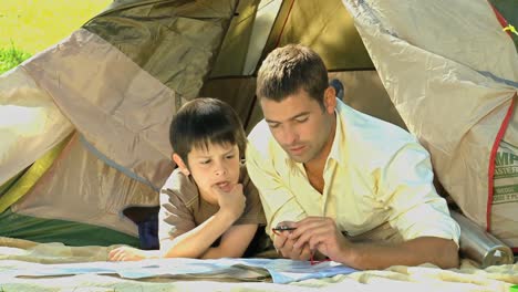 Vater-Und-Sohn-Betrachten-Eine-Karte-In-Der-Nähe-Eines-Zeltes