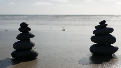 rock balancing on ocean beach, stones stacking by sea water waves. pyramid of pebbles on sandy shore