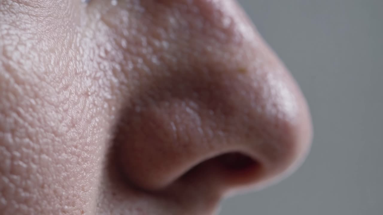 Close-up side view of a human nose, showcasing skin texture in high detail