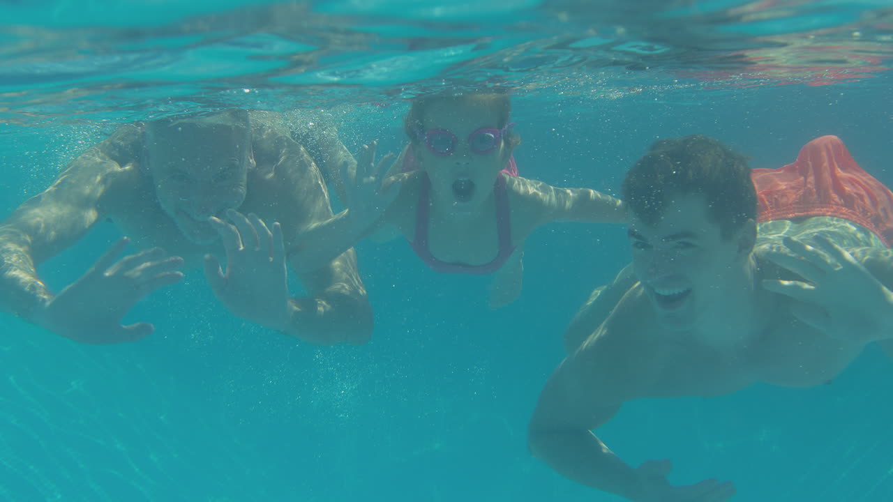 여름 휴가 중 수영장에서 카메라를 향해 손을 흔들고 있는 다세대 가족