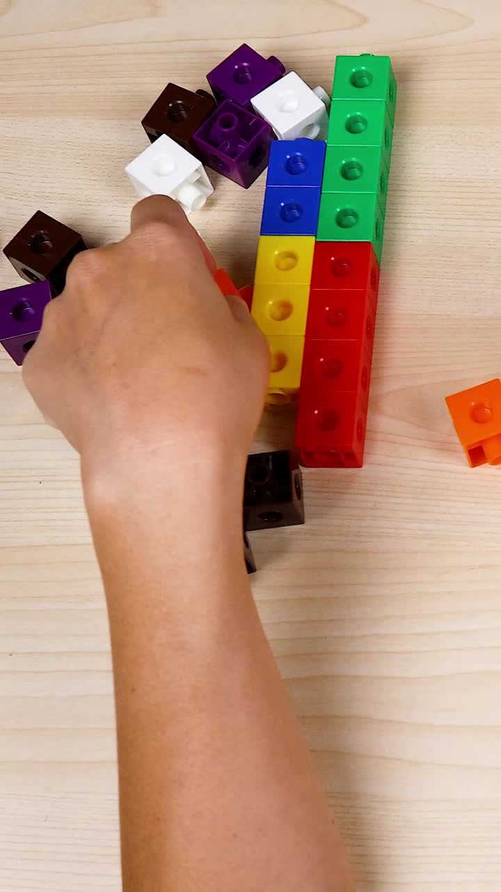 Hands assembling colorful linking cubes on table