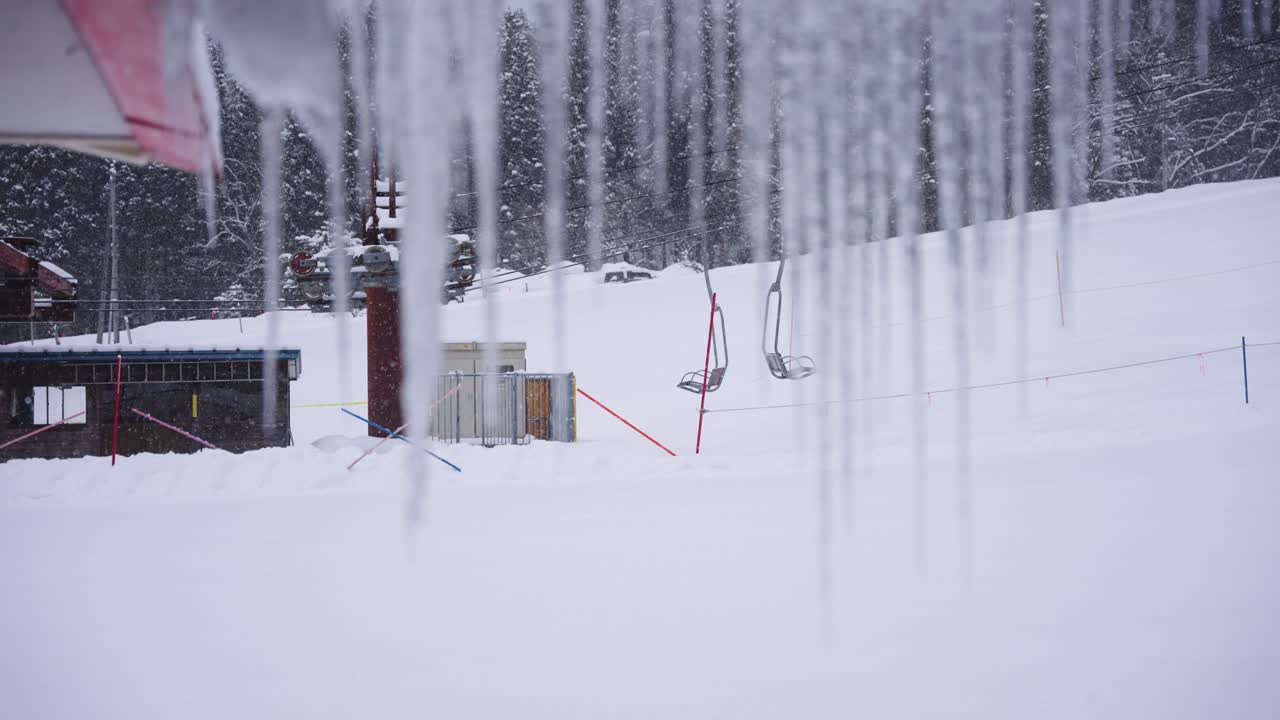 얼어붙은 고드름 뗏목은 눈 속의 스키장에서 의자 리프트를 드러내기 위해 초점을 맞춥니다