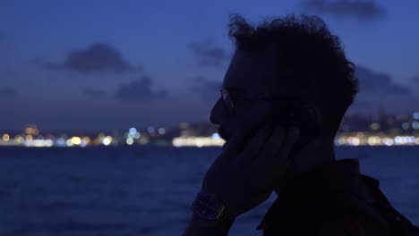 man talking on the phone on the ferry at night. dark.