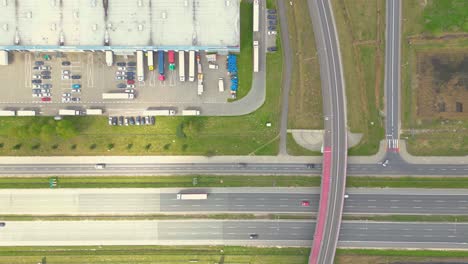 Logistics-park-with-warehouse,-loading-hub-and-many-semi-trucks-with-cargo-trailers-standing-at-the-ramps-for-load-unload-goods-at-sunset