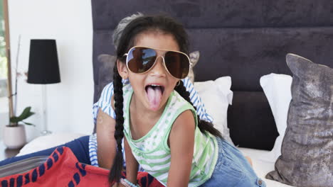 Biracial-girl-with-braided-hair-wears-large-sunglasses-and-a-striped-tank-top