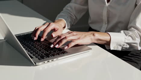 close-up of a person's hands typing on a laptop keyboard