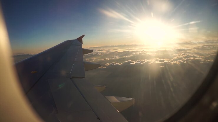 La vue imprenable du soleil brillant au-dessus des nuages depuis un avion de ligne - Plan moyen