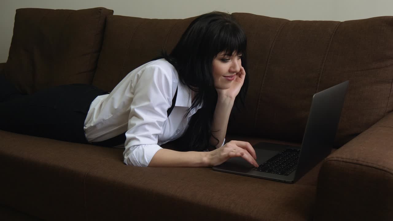 소파에 앉아 있는 집에서 노트북을 사용하는 젊은 여성