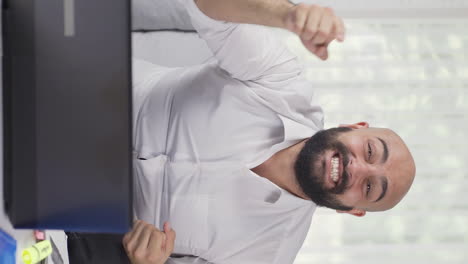 Vertical-video-of-Home-office-worker-man-experiencing-joy-looking-at-camera.