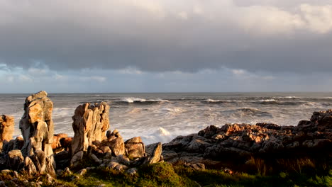 Vista-En-Cámara-Lenta-De-Una-Ola-Rompiendo-Contra-Las-Rocas-Costeras,-Creando-Rocío-En-Hermanus