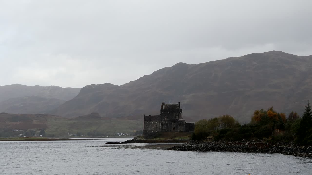 castillo de eilean donan, tierras altas, escocia, con cielos oscuros y nubes y montañas