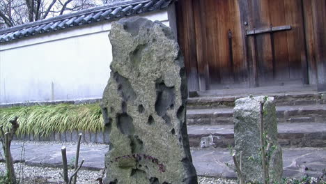 a rock slab stands at the entrance of a japanese courtyard