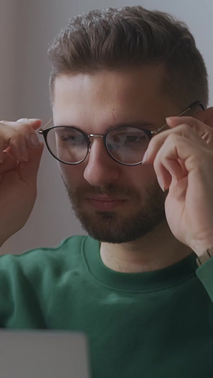 Jovem Homem Coloca Óculos e se Concentra no Trabalho