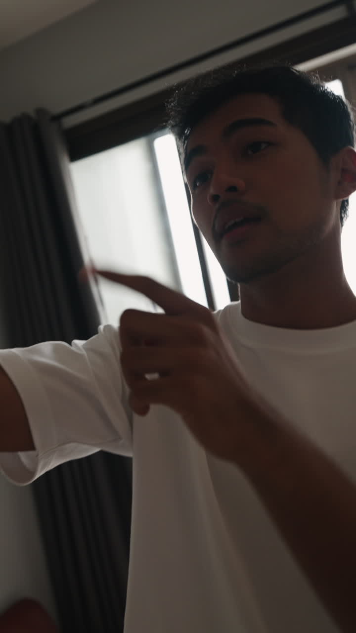 Man in white shirt pointing indoors