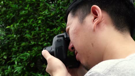 rear side view of young male photographer taking photos in nature scenery