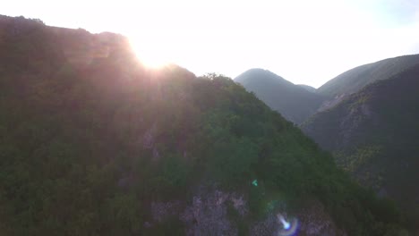 sun ray behind mountain outside of novi pazar in serbia europe, aerial descending