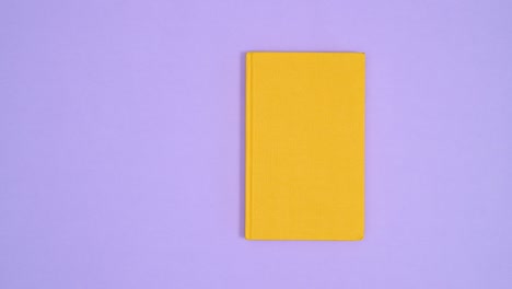 yellow hardcover retro vintage book move left right on purple theme and open. stop motion flat lay