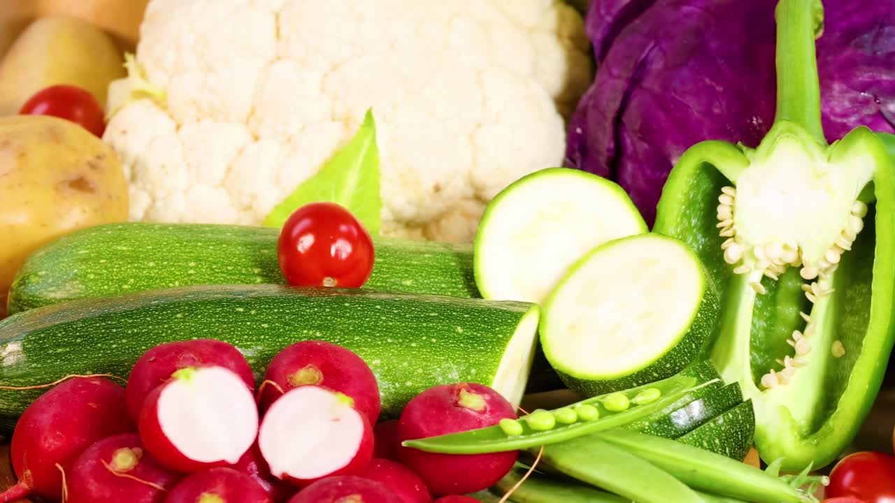 A colorful assortment of fresh vegetables including zucchini, radishes, and bell peppers arranged together.